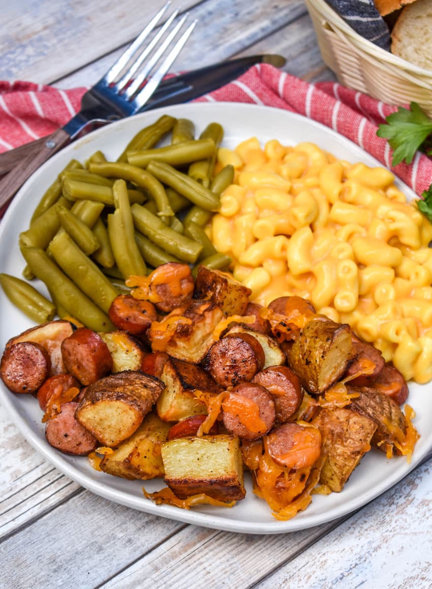 cheesy sheet pan hot dogs and potatoes on a white plate