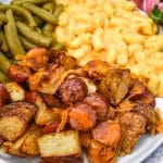 cheesy sheet pan hot dogs and potatoes on a white plate