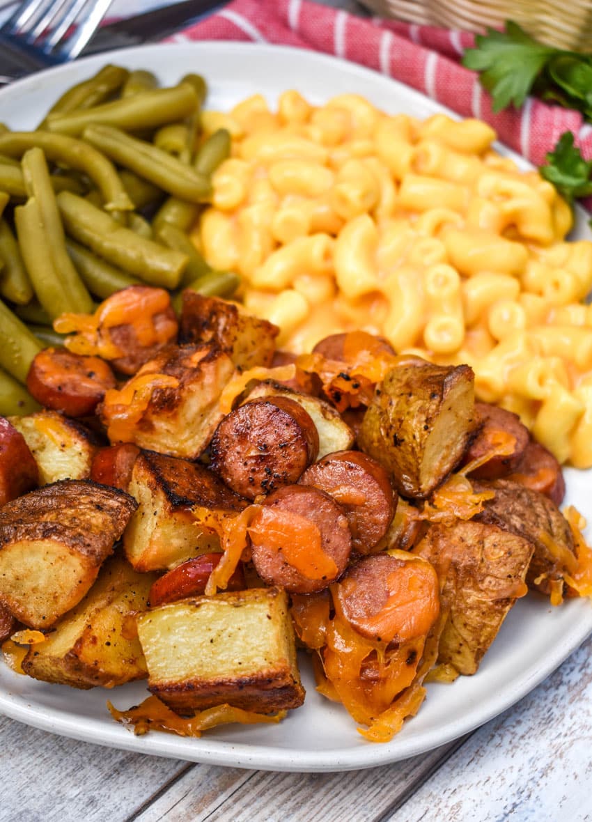 cheesy sheet pan hot dogs and potatoes on a white plate