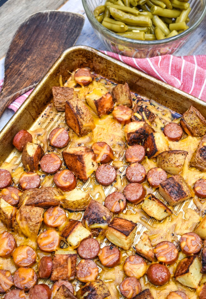 cheesy hot dogs and potatoes on a metal sheet pan