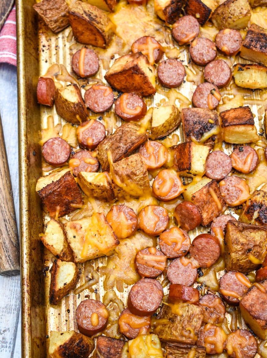 cheesy hot dogs and potatoes on a metal sheet pan
