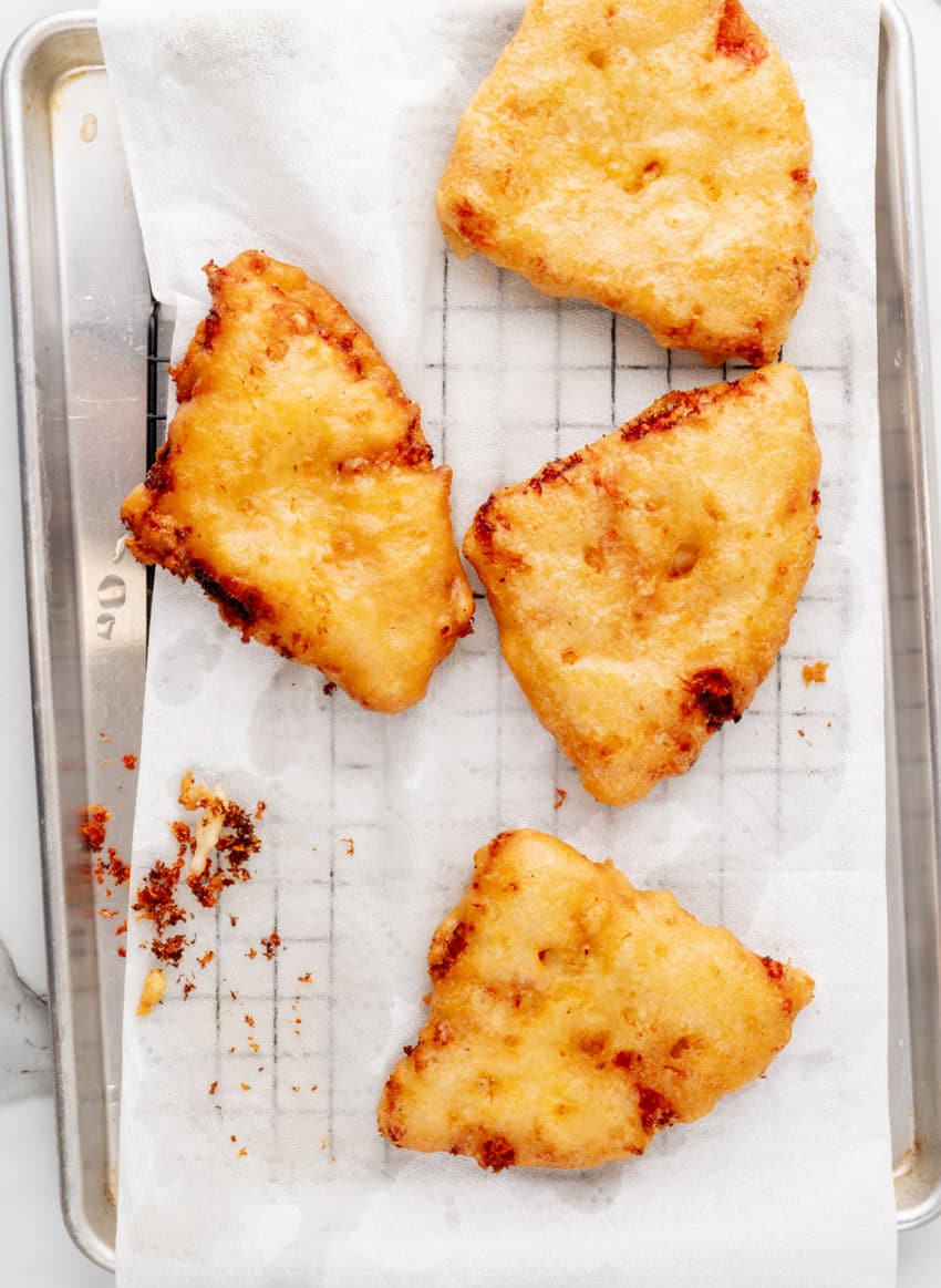 deep fried slices of frozen pizza draining on parchment papper