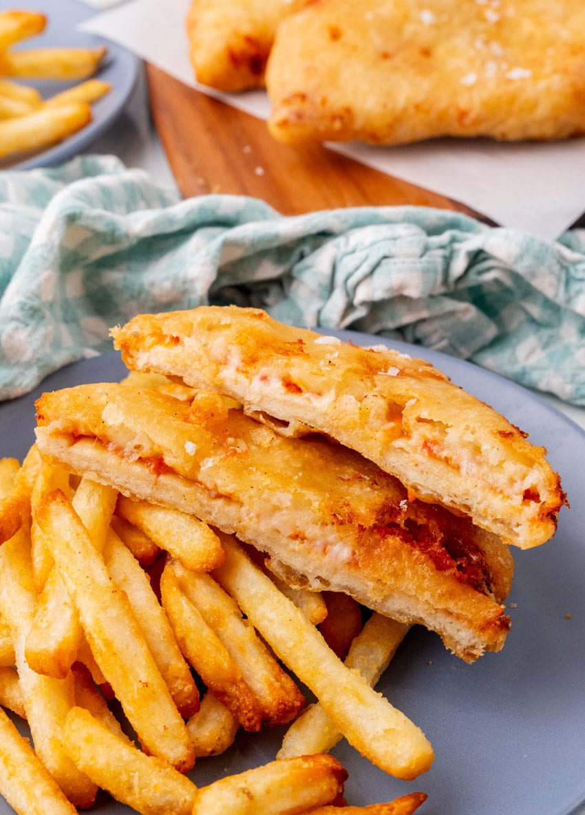 slices of homemade pizza crunch next to crispy french fries on a blue plate