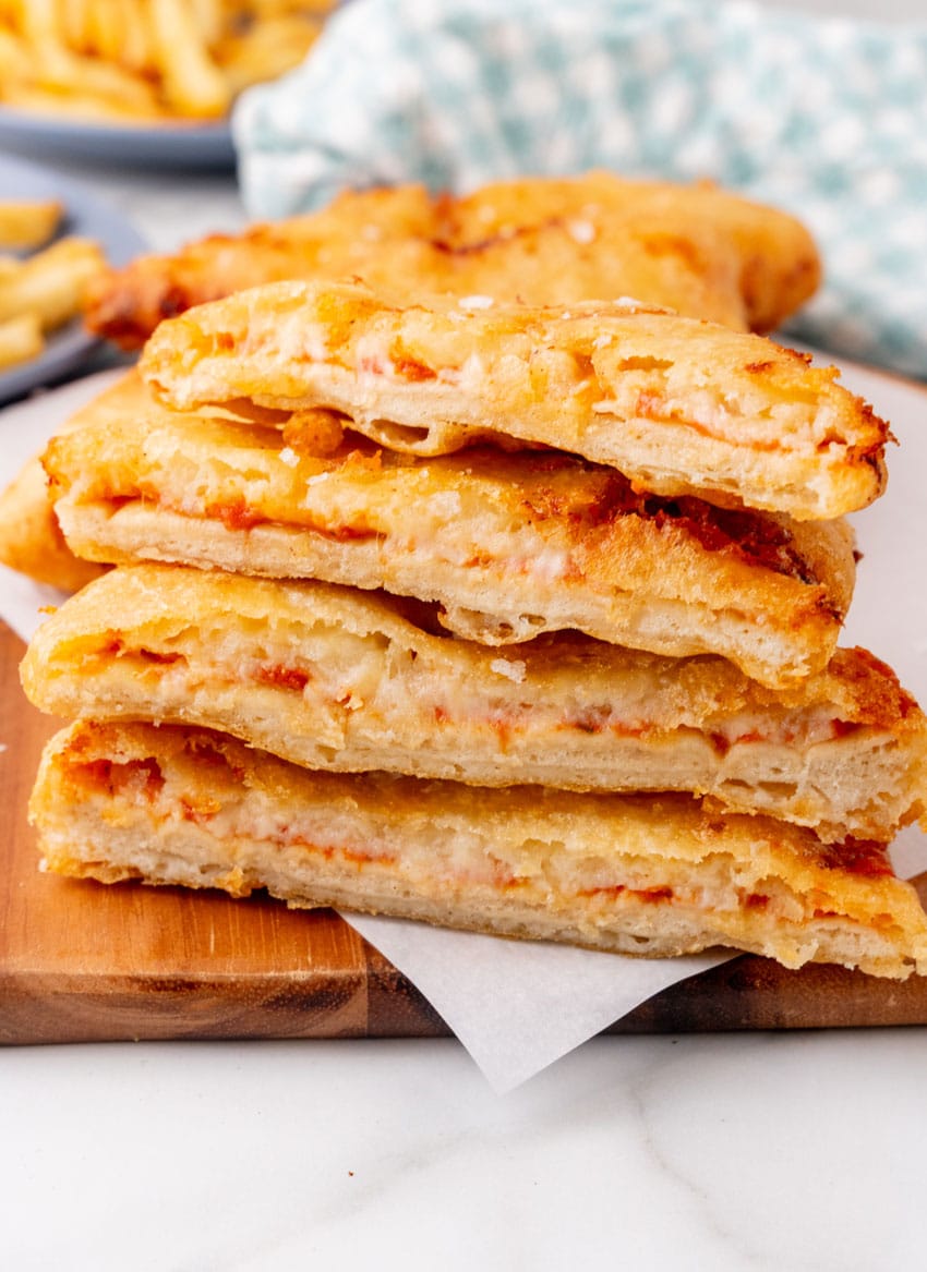 slices of pizza crunch stacked on a parchment paper lined wooden cutting board