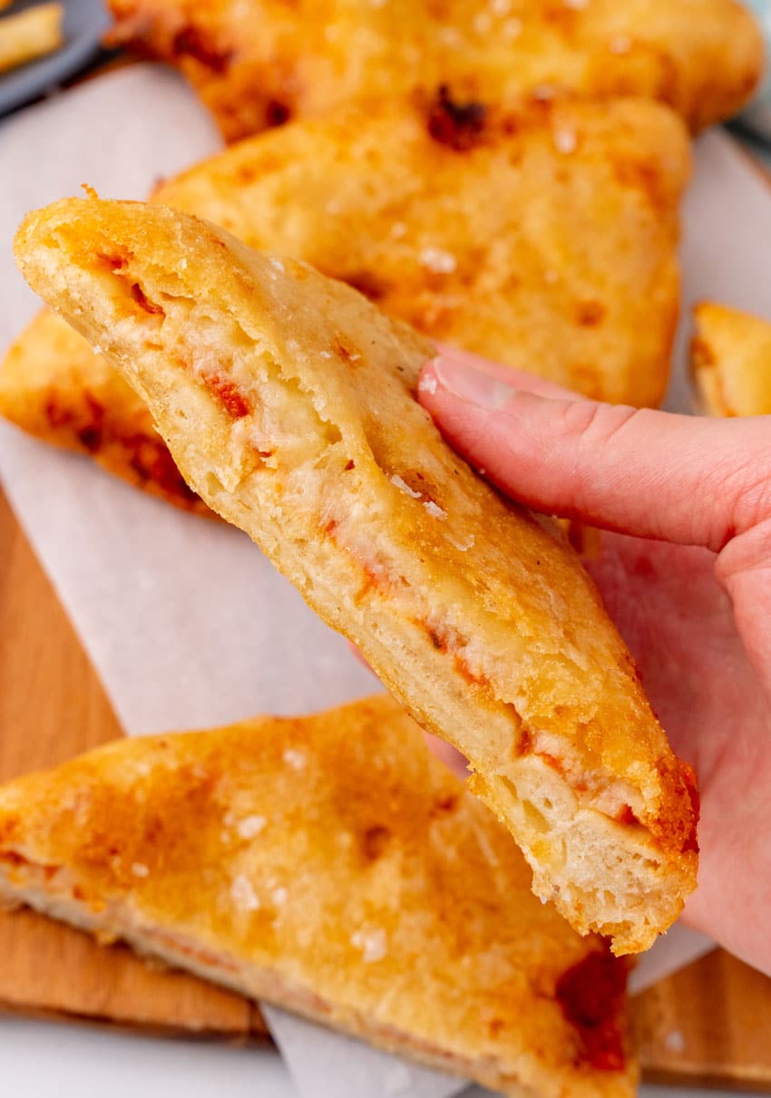 a hand holding up a a slice of a homemade pizza crunch recipe