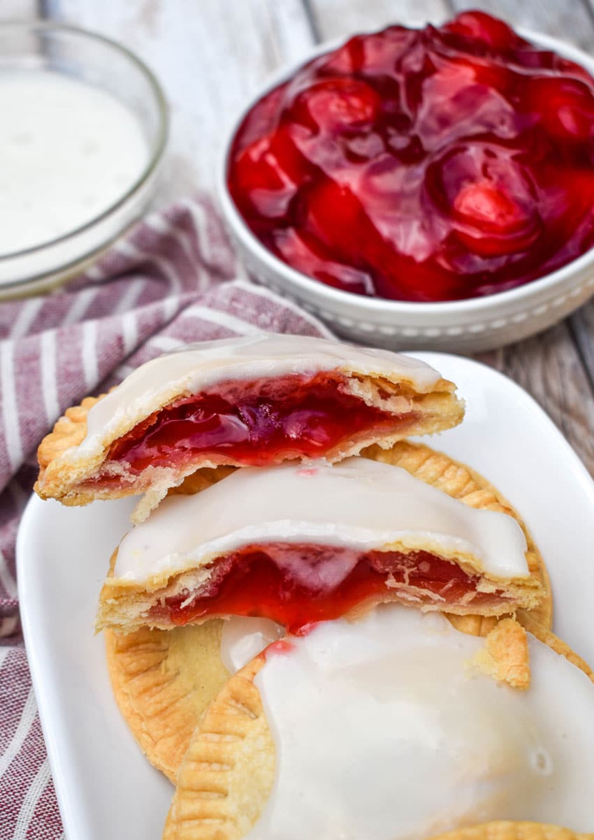 a pile of air fried glazed cherry hand pies on a wooden table