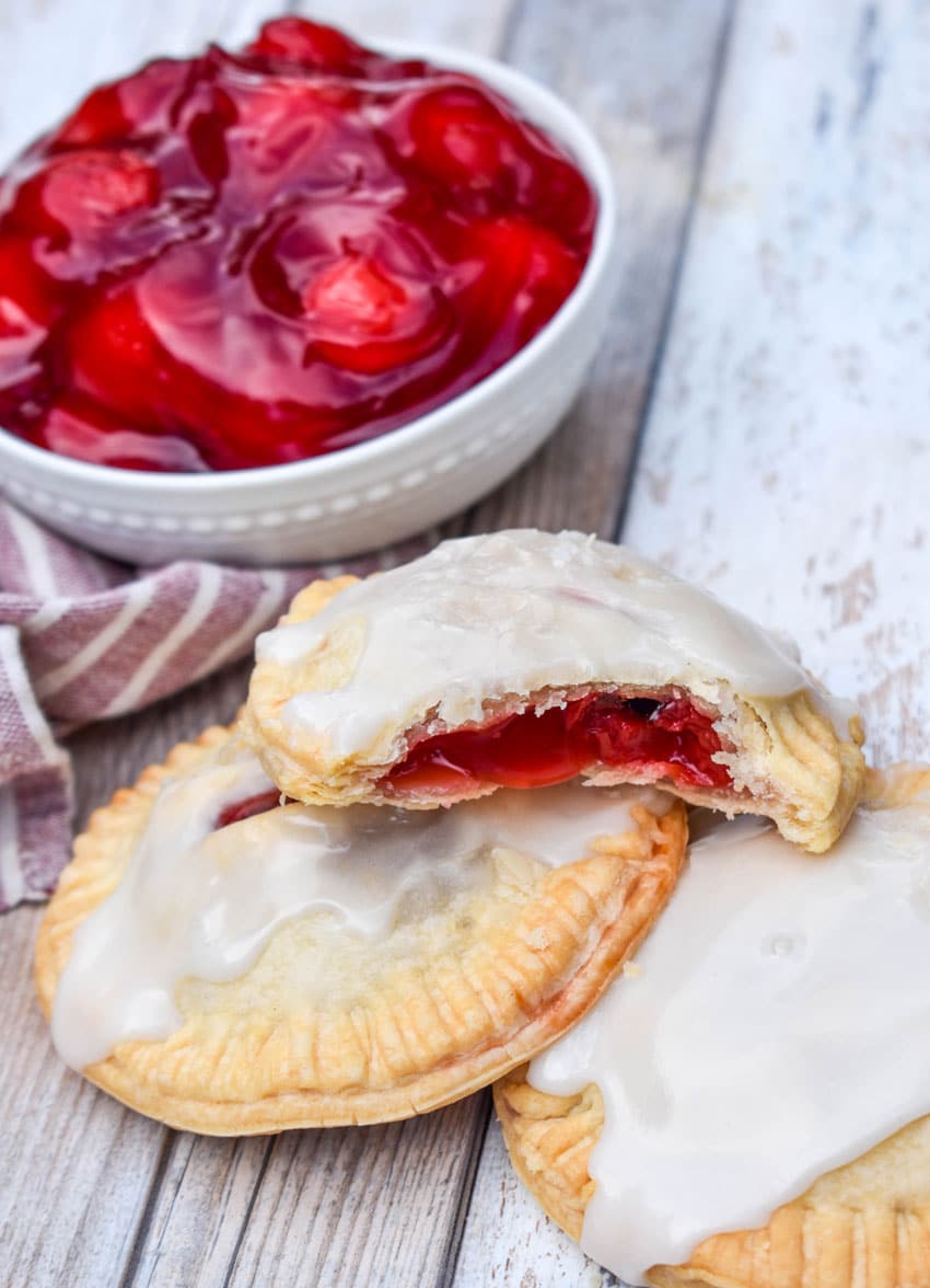a pile of air fried glazed cherry hand pies on a wooden table