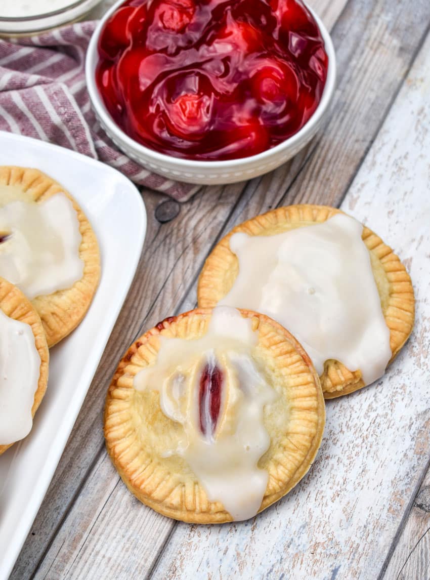 a pile of air fried glazed cherry hand pies on a wooden table