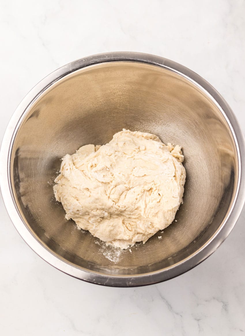 homemade pizza dough in a stainless steel mixing bowl