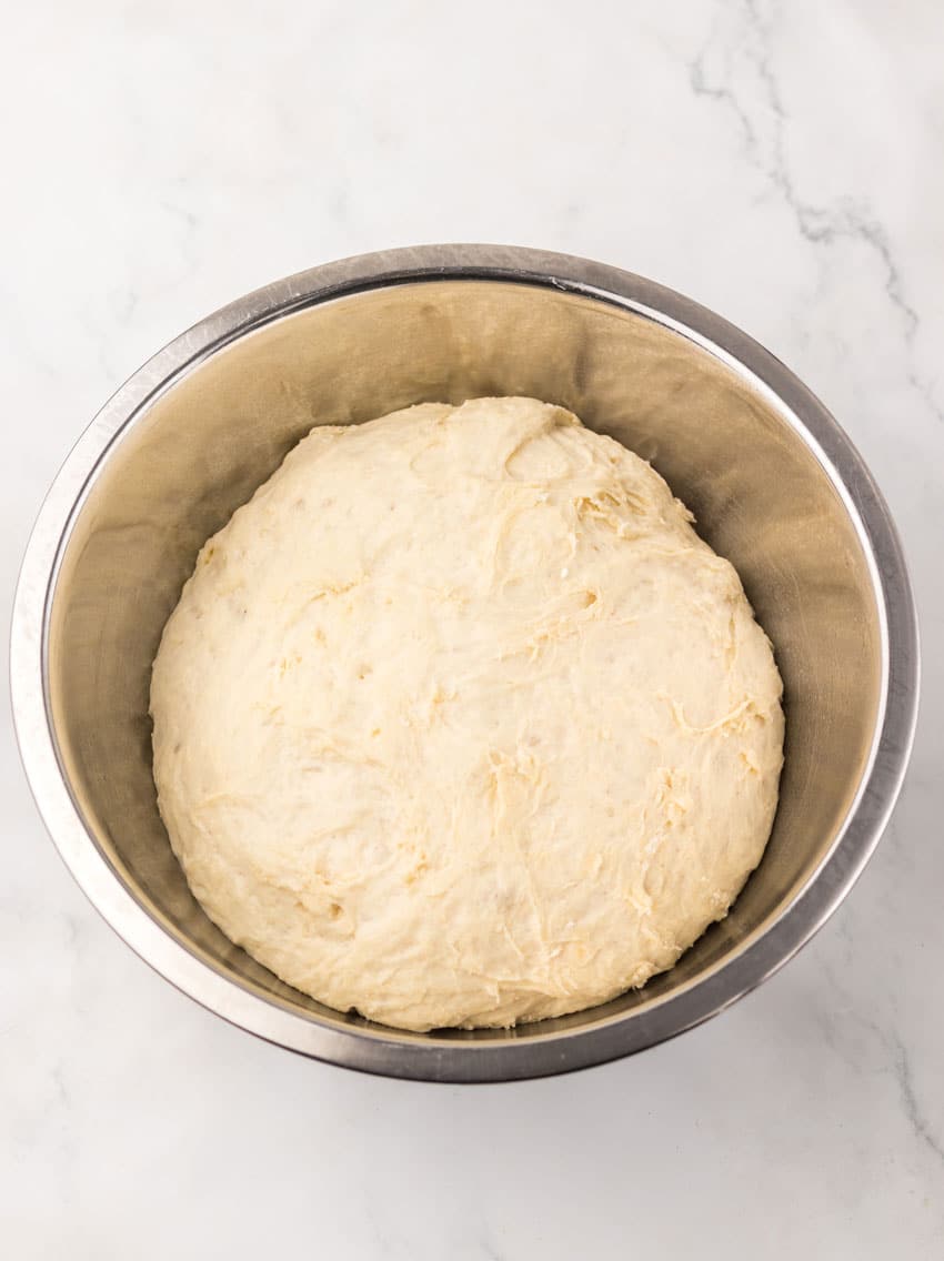 homemade pizza dough in a stainless steel mixing bowl