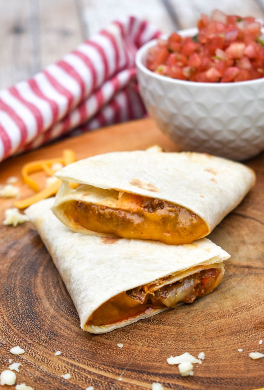 copycat taco bell meximelt halves stacked on a wooden cutting board