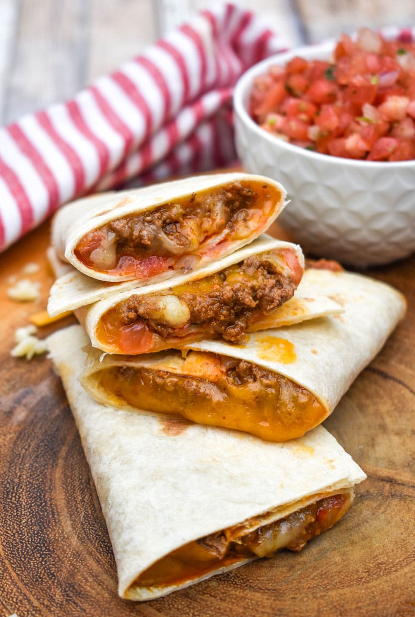 homemade taco bell mexi melts stacked on a wooden cutting board
