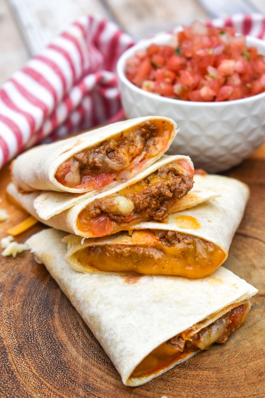 homemade taco bell mexi melts stacked on a wooden cutting board