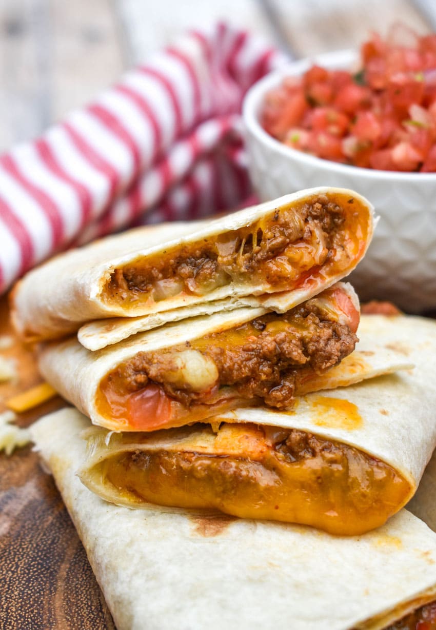 homemade taco bell mexi melts stacked on a wooden cutting board