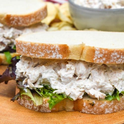creamy french onion dip chicken salad sandwich on a wooden cutting board