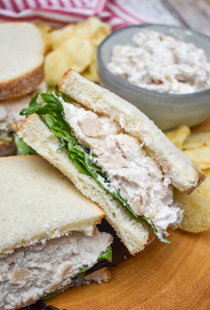 creamy french onion dip chicken salad sandwich on a wooden cutting board