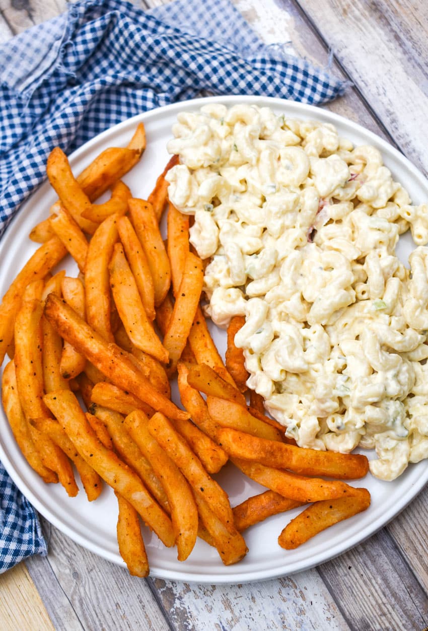 a half layer of french fries next to a half layer of creamy macaroni salad together on a white plate