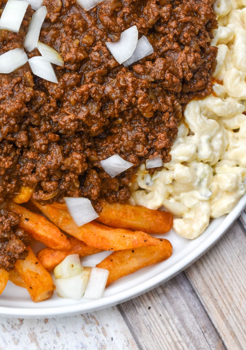 french fries and macaroni salad topped with hot dog chili on a white plate