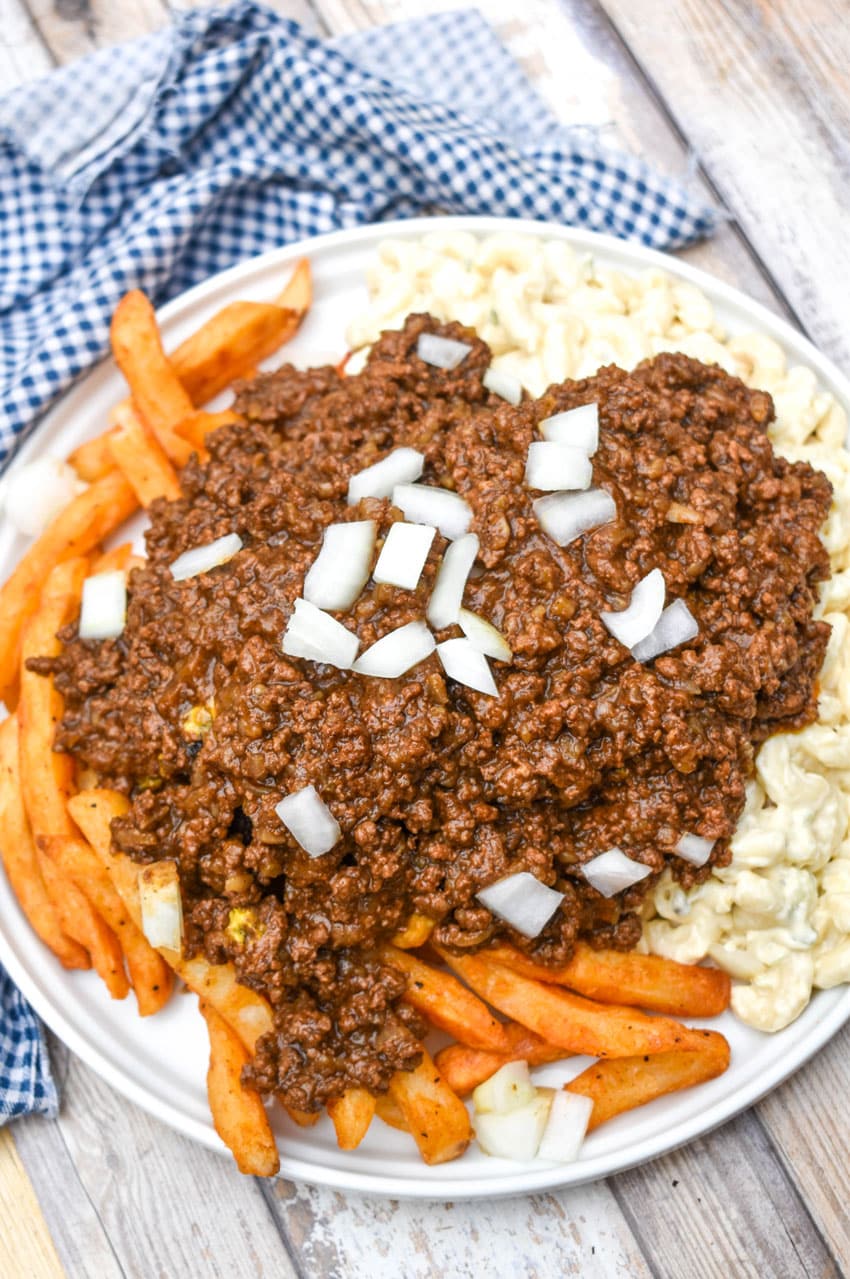 an overhead image showing a homemade new york style garbage plate on a wooden picnic table