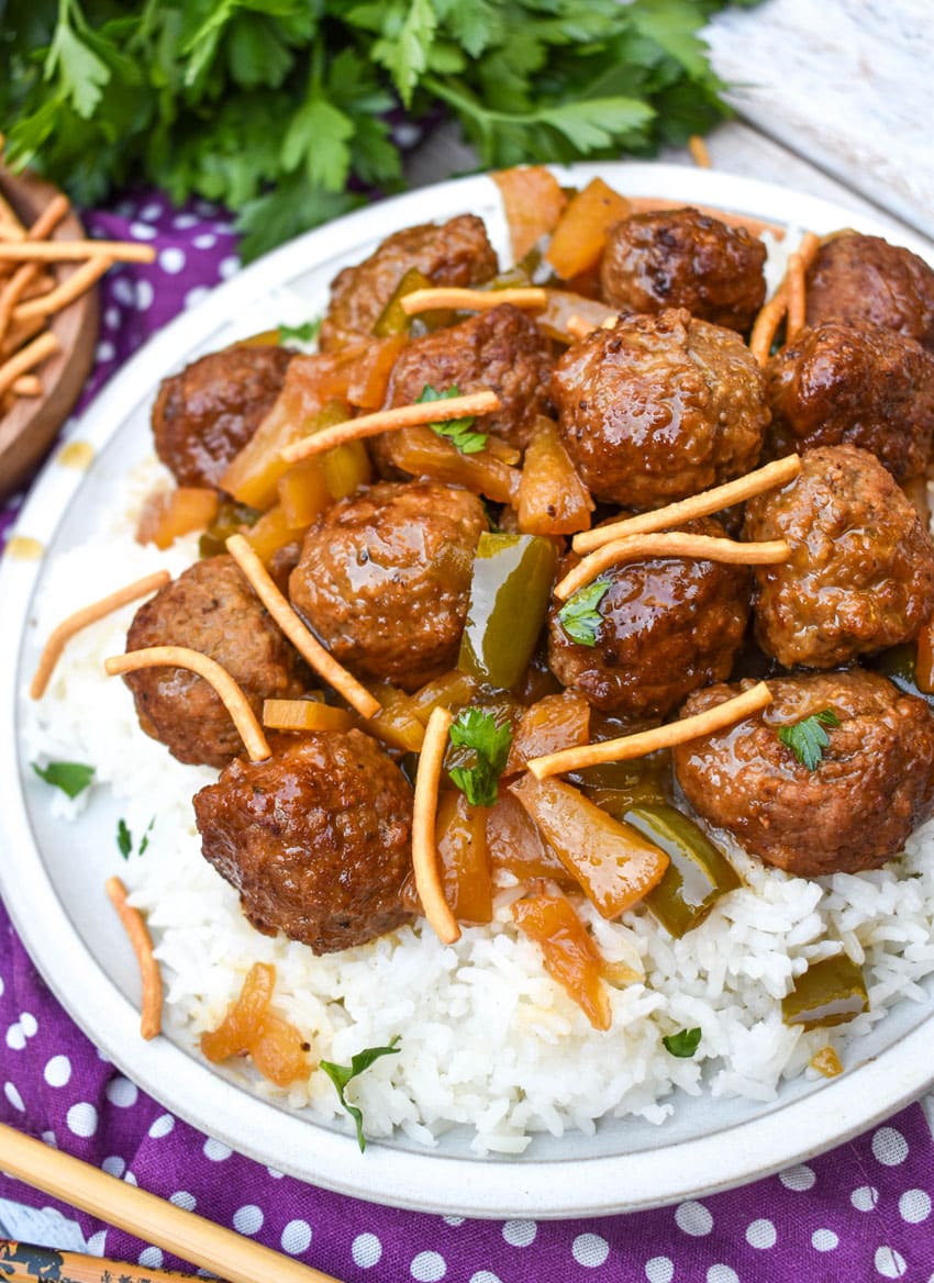 slow cooker sweet and sour meatballs over steamed white rice on a white plate