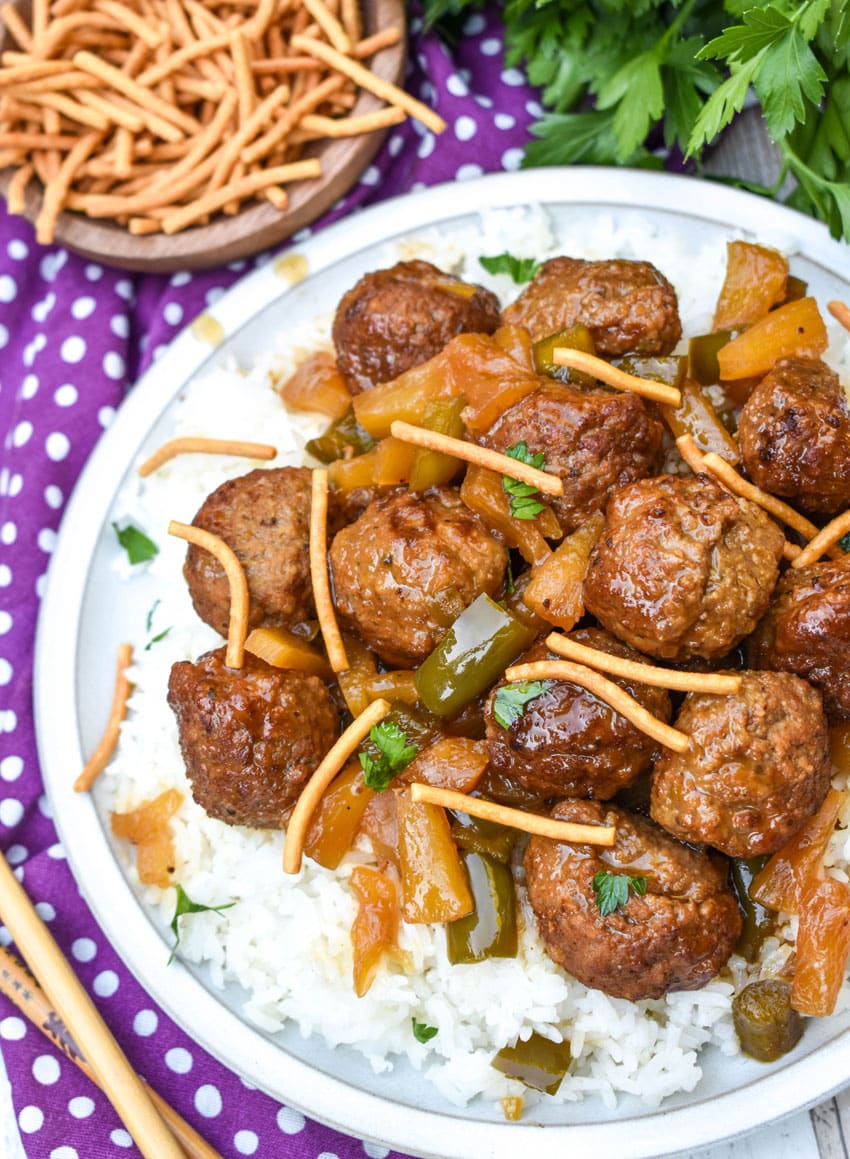 slow cooker sweet and sour meatballs over steamed white rice on a white plate