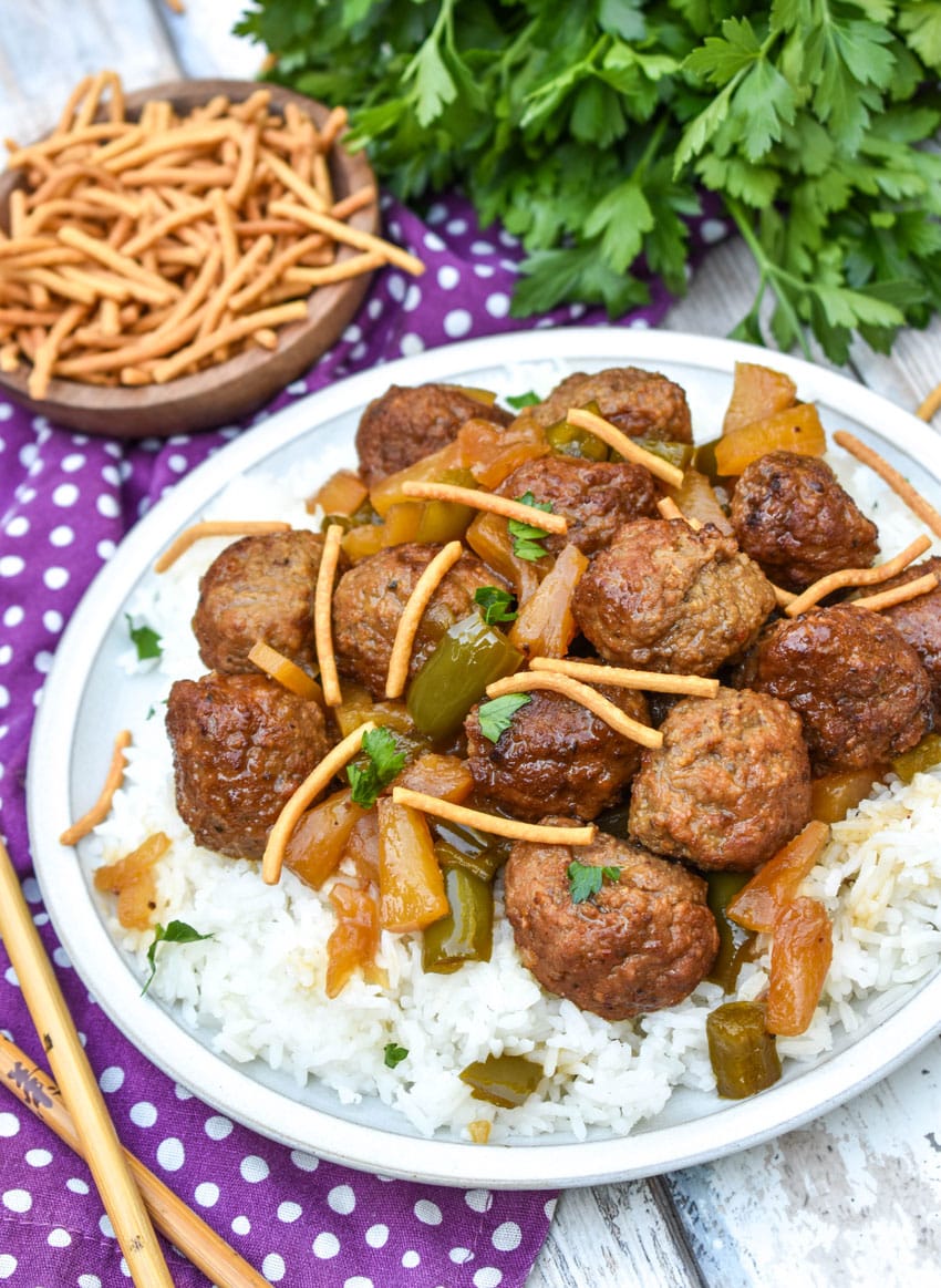 slow cooker sweet and sour meatballs over steamed white rice on a white plate