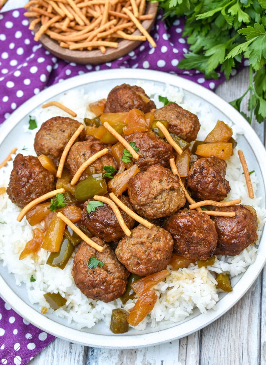 slow cooker sweet and sour meatballs over steamed white rice on a white plate