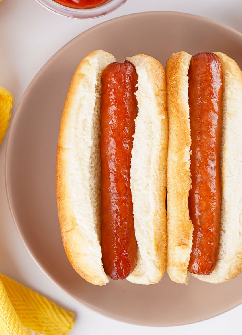 two air fried hot dogs in buns on a gray plate
