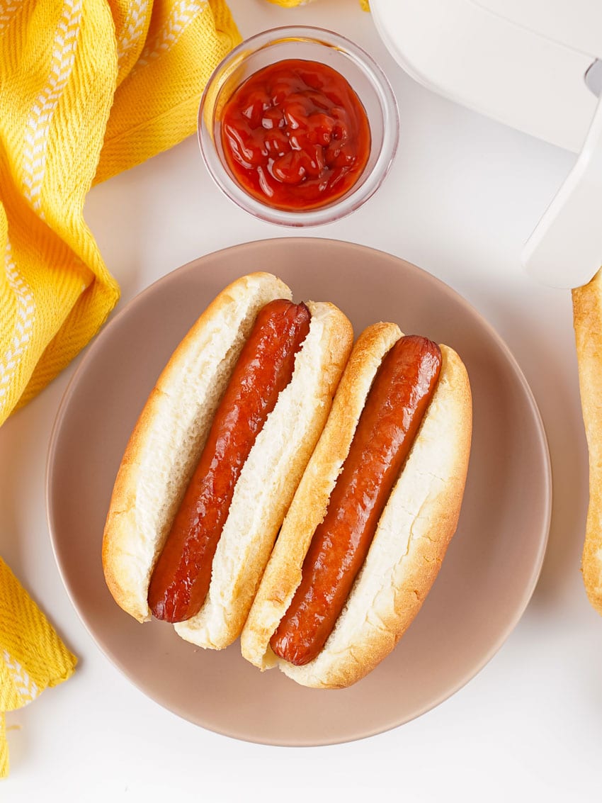 two air fryer hot dogs in fluffy buns on a gray plate