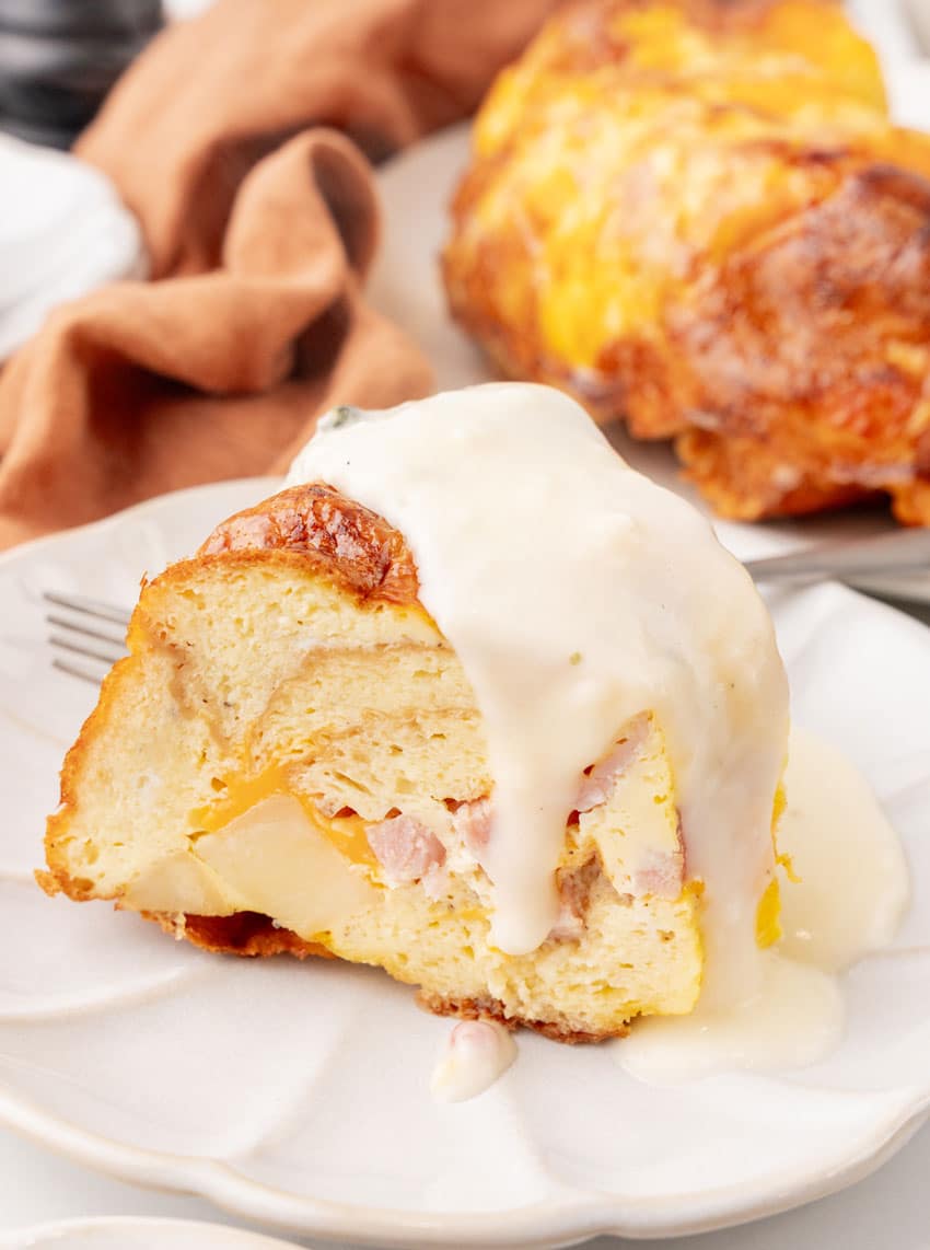 a slice of a breakfast bundt bake on a white plate with a silver fork resting on the side