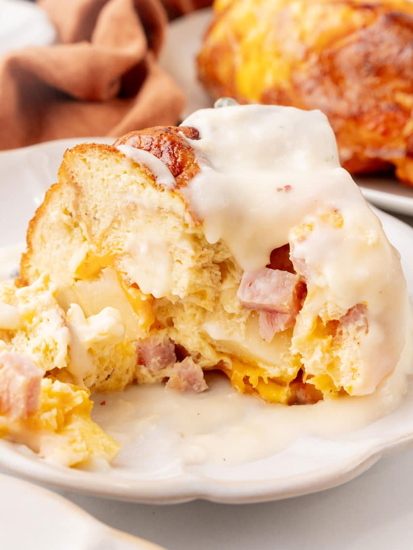 a slice of a breakfast bundt bake on a white plate with a silver fork resting on the side