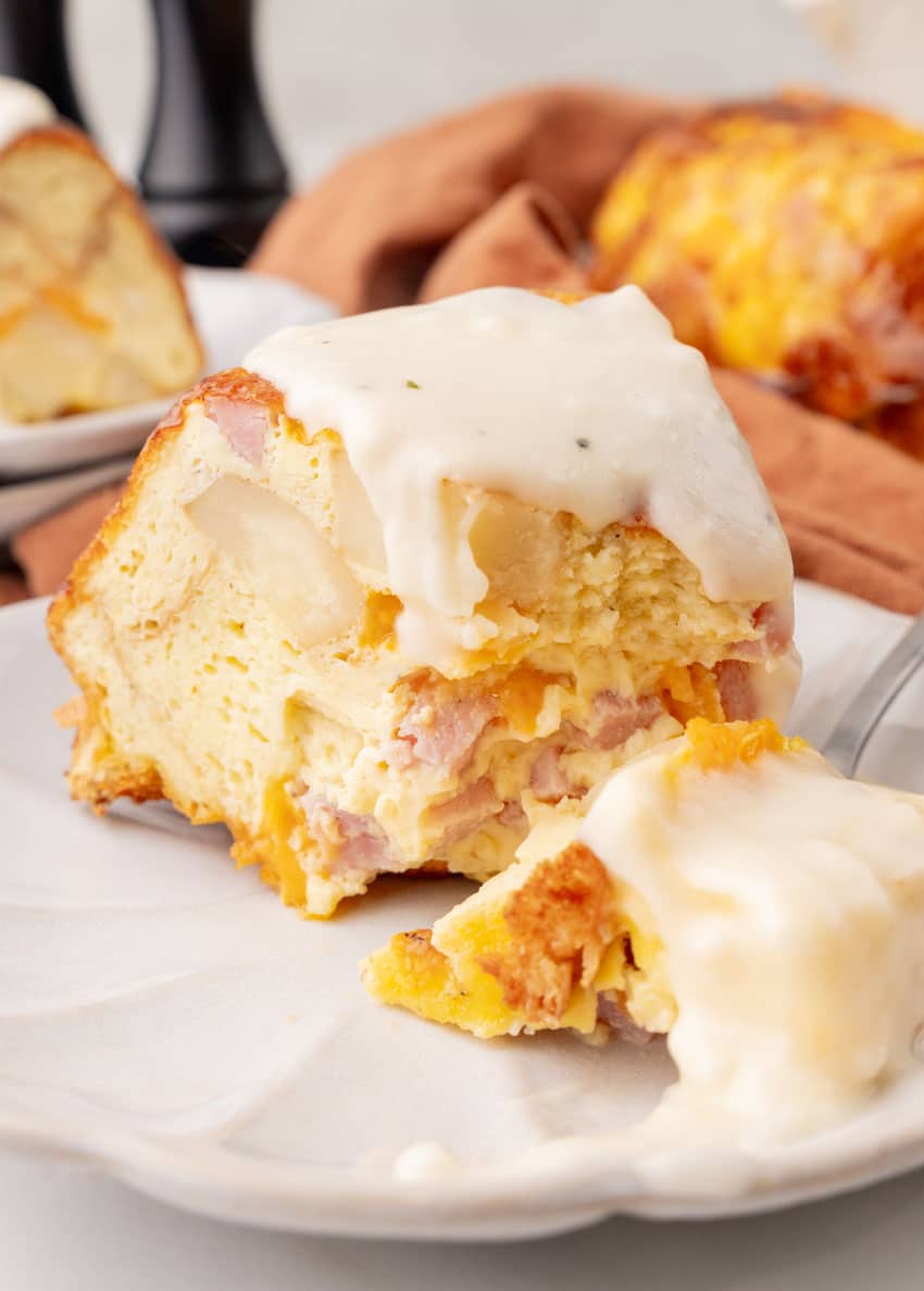 a slice of a breakfast bundt bake on a white plate with a silver fork resting on the side