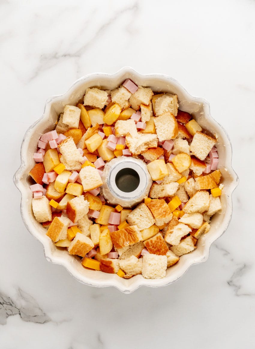 bread cubes, diced ham, and cubes of cheddar cheese in a bundt pan