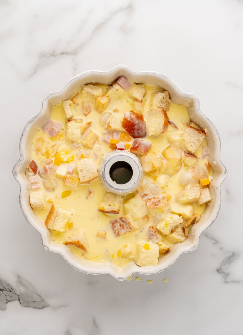diced ham, cheese cubes, baguette pieces soaking in beaten eggs in a bundt pan
