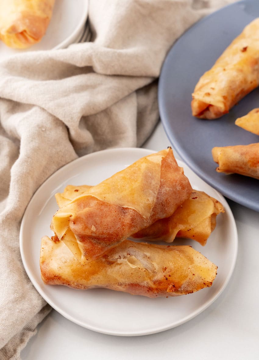 two pepperoni cheese stuffed egg rolls on a small white appetizer plate