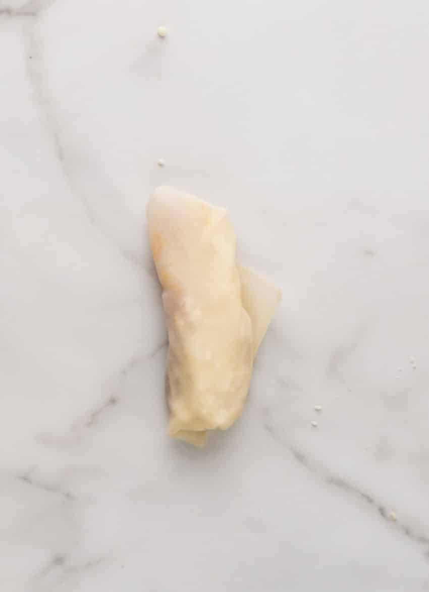 a rolled disney copycat pepperoni spring roll resting on a marble counter top