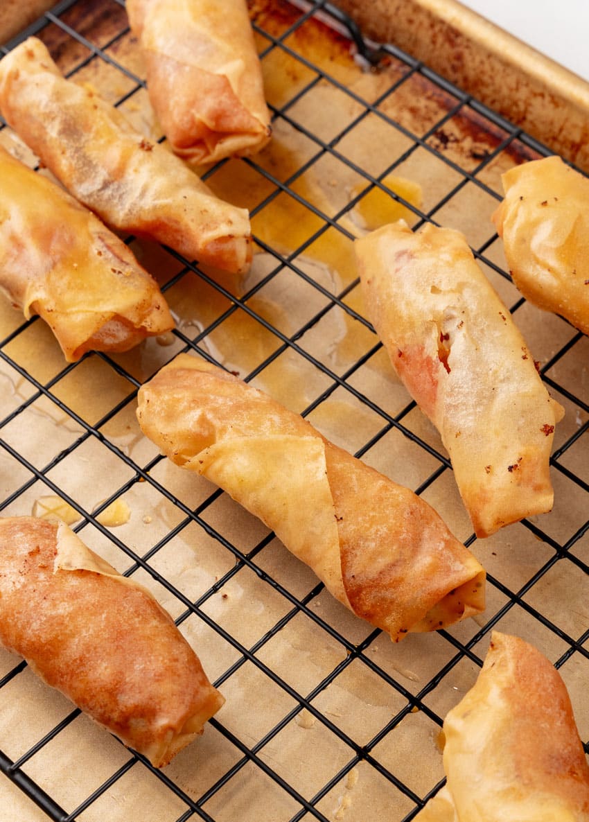 pepperoni and cheese stuffed fried egg rolls resting on a wire cooling rack
