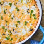 cheesy chicken enchilada dip in a cast iron skillet surrounded by tortilla chips