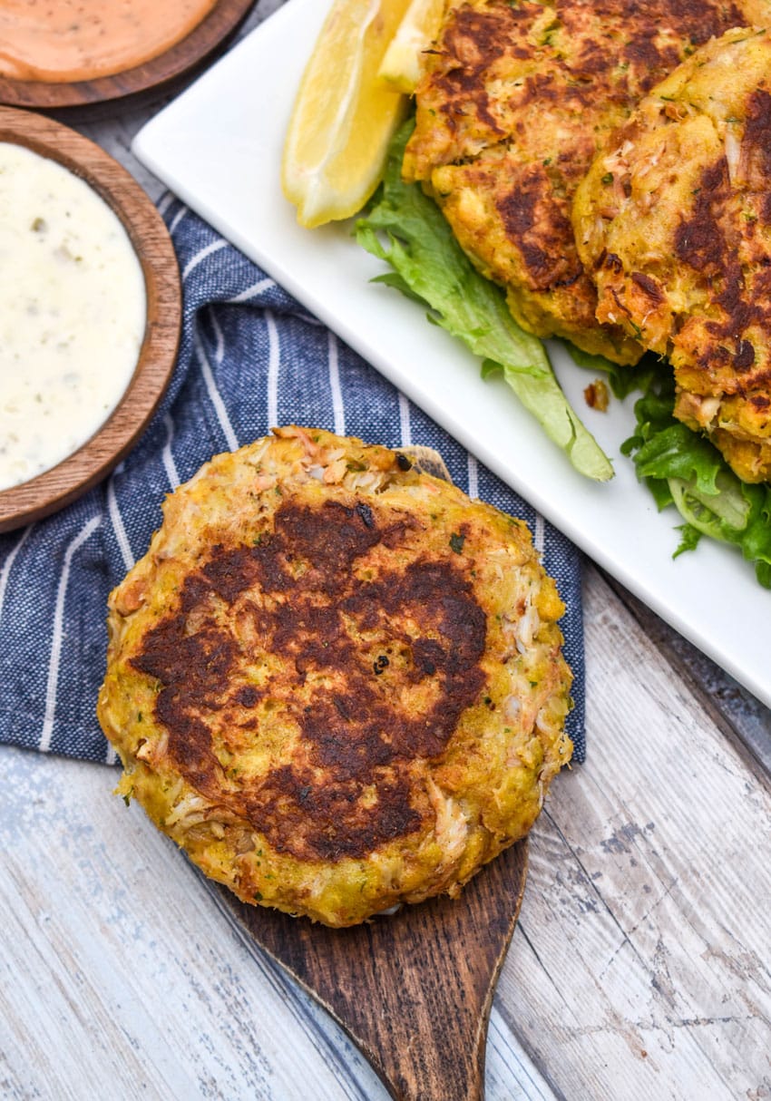 a crispy cornbread stuffing crab cake resting on a wooden spatula