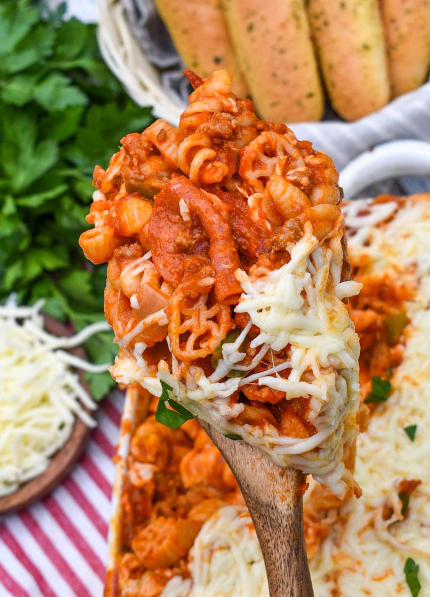 a wooden spoon holding up a scoop of cheesy cavatini supreme pasta
