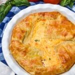a tomato pie with puff pastry crust in a white pie dish