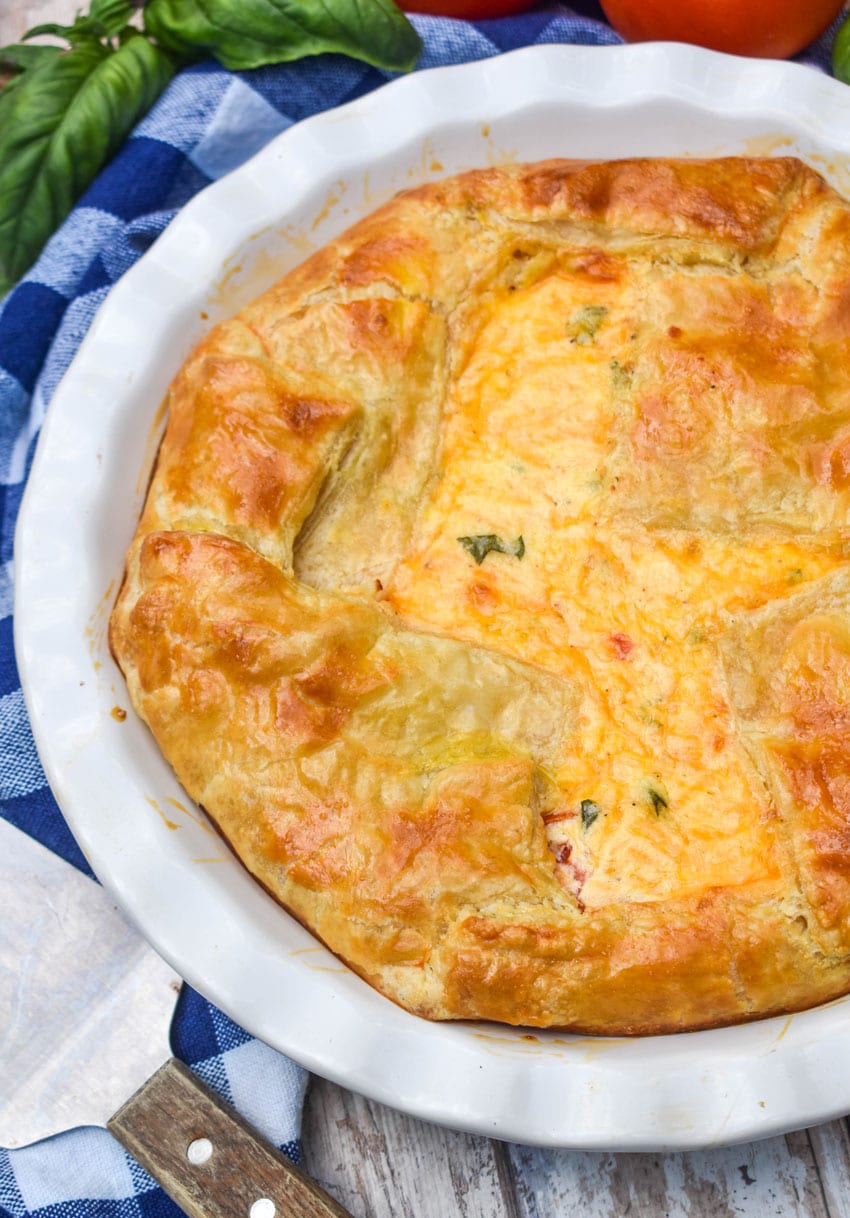 a tomato pie with puff pastry crust in a white pie dish
