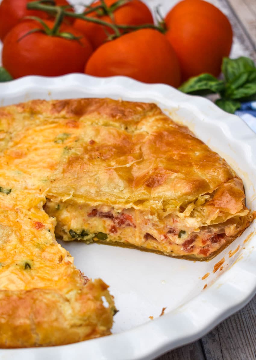 a tomato pie with puff pastry crust in a white pie dish
