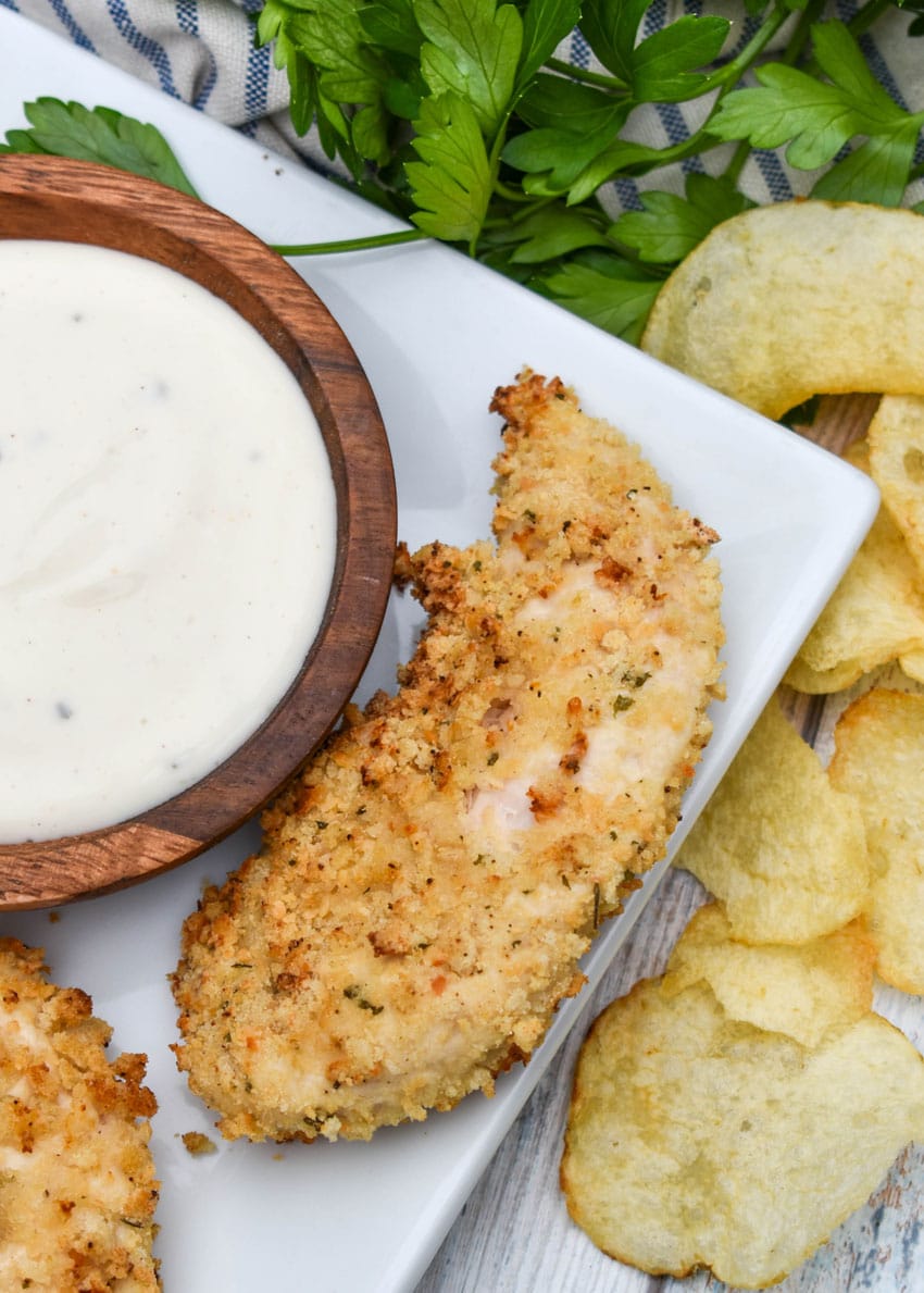 air fryer ranch chicken tenders on a white serving platter with a small bowl of ranch dressing on the side for dipping