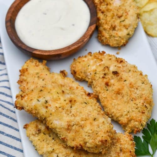 air fryer ranch chicken tenders on a white serving platter with a small bowl of ranch dressing on the side for dipping