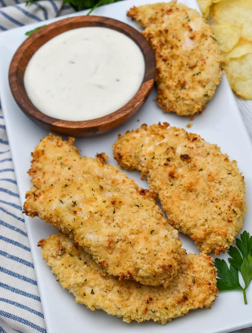 air fryer ranch chicken tenders on a white serving platter with a small bowl of ranch dressing on the side for dipping