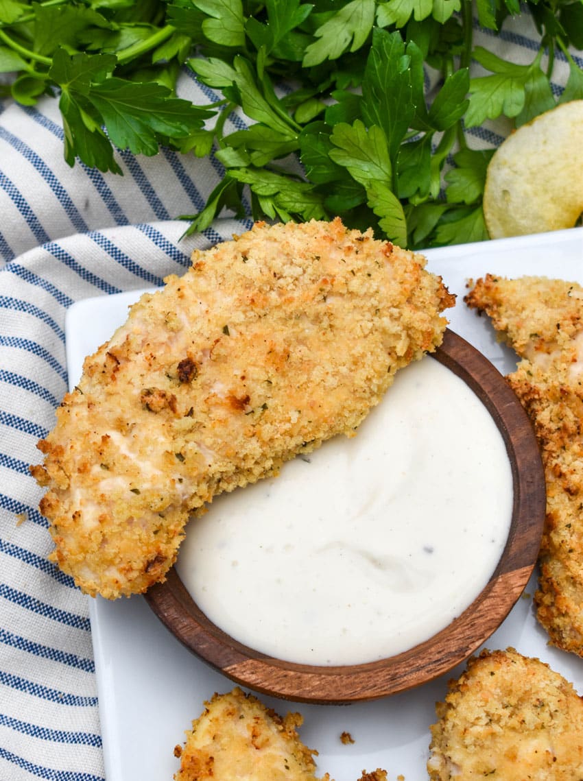 air fryer ranch chicken tenders on a white serving platter with a small bowl of ranch dressing on the side for dipping