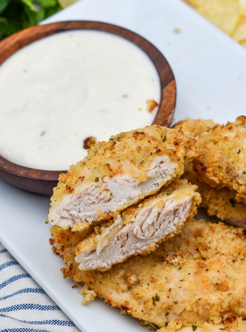 air fryer ranch chicken tenders on a white serving platter with a small bowl of ranch dressing on the side for dipping