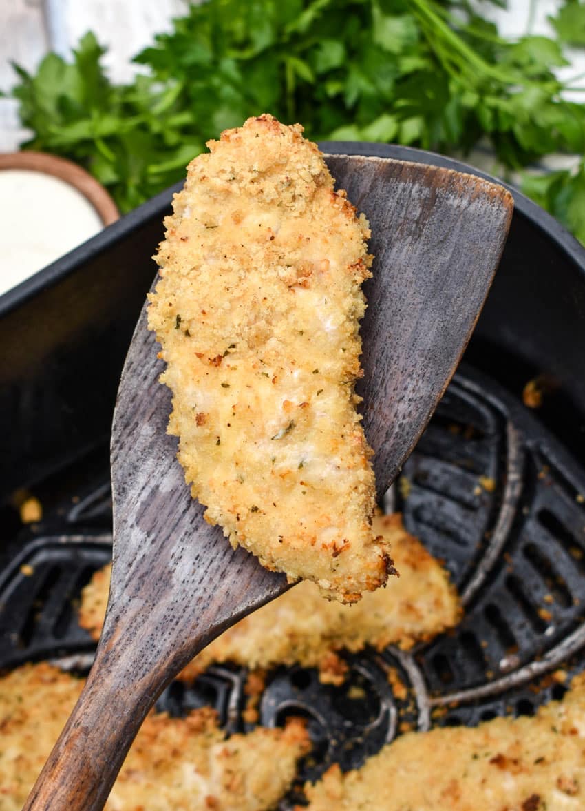 a wooden spatula holding up a ranch seasoned air fried chicken tender