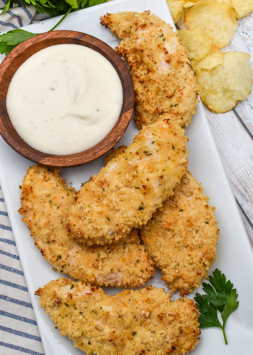 air fryer ranch chicken tenders on a white serving platter with a small bowl of ranch dressing on the side for dipping